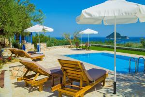 een zwembad met stoelen en een tafel met een parasol bij Villa Vakis in Lithakia