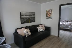 a living room with a black couch and a bed at Hlidarbol Apartments in Hlíðarendi