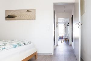 ein weißes Schlafzimmer mit einem Bett und einem Flur in der Unterkunft Ferienwohnung im Fischerhäusle in Nonnenhorn