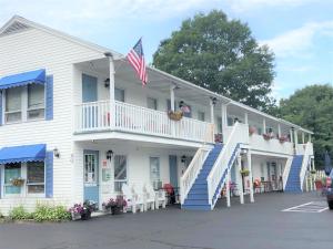 a white house with a porch and an american flag at Seacoast Motel in Wells