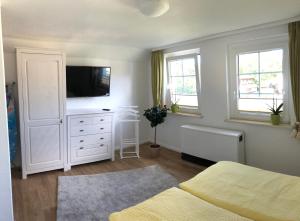 a bedroom with a white dresser with a flat screen tv at Sommerhaus Boldevitz auf Rügen in Boldevitz