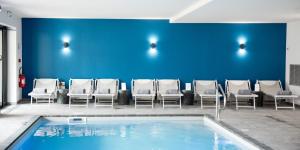 uma piscina numa sala de espera com cadeiras e uma parede azul em Armes de Champagne em Châlons-en-Champagne