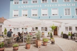 eine Gruppe von Personen, die vor einem Gebäude an Tischen sitzen in der Unterkunft Landhotel Stegersbach in Stegersbach