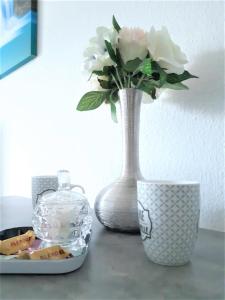 un vaso con dei fiori, seduto su un tavolo. di Comfort Stay Basel Airport 1A46 a Saint-Louis
