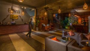 a man walking through a lobby with couches and a bar at La Rivière d' Angkor Resort in Siem Reap