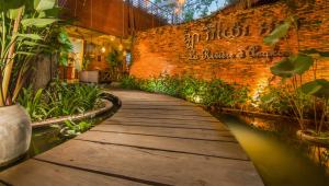a wooden walkway in a building with plants at La Rivière d' Angkor Resort in Siem Reap