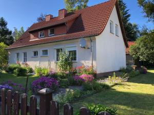 a white house with a red roof and flowers at Sommerhaus Boldevitz auf Rügen in Boldevitz