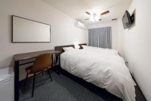 - une chambre avec un lit et un bureau avec une chaise dans l'établissement Rota Hostel, à Osaka