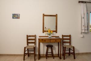un tavolo con due sedie e uno specchio su una parete di Olga Apartments ad Alinda