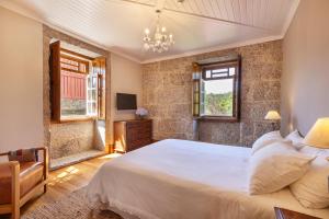 een slaapkamer met een groot wit bed en een kroonluchter bij Casa do Eido - sustainable living & nature experiences Gerês in Geres +76 foto's