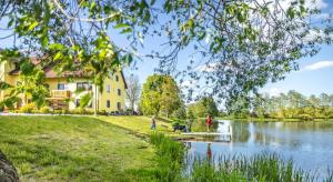 a house next to a lake with people walking a dog at Bartlhof-Ferienwohnungen-Zimmer in Burglengenfeld