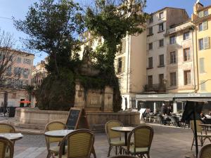 uma área de estar exterior com mesas, cadeiras e edifícios em 2 pièces avec grande terrasse - Centre de Toulon em Toulon
