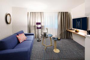 - un salon avec un canapé bleu et une table dans l'établissement Grand Hotel Bregenz - MGallery Hotel Collection, à Bregenz