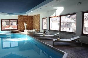 a swimming pool with lounge chairs in a building at Royal Olympic Hotel in Pinzolo