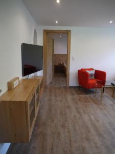 a living room with a flat screen tv and a red chair at Haus Schmid in Tobadill