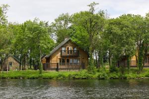 a wooden house with a balcony next to a river at Lusty Beg Island in Kesh