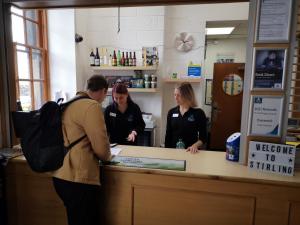 três pessoas em pé num balcão numa loja em Stirling Youth Hostel em Stirling