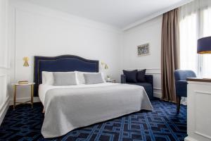 Hotel Midmost by Majestic Hotel Group في برشلونة: غرفة فندقية بسرير كبير وكرسي