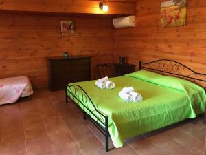 una camera da letto con un letto verde e asciugamani di Baita Liverpool a Vieste