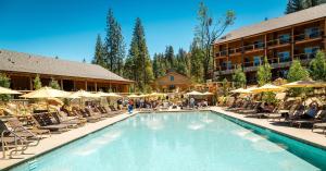 una piscina in un hotel con sedie e ombrelloni di Rush Creek Lodge at Yosemite a Groveland