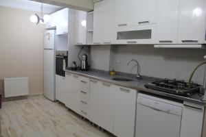 una cocina con armarios blancos y electrodomésticos de acero inoxidable en Bedir Apartments, en Estambul