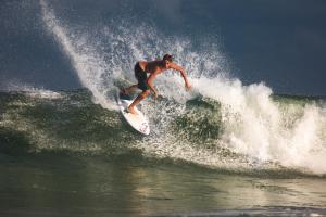 un homme faisant une vague sur une planche de surf dans l'océan dans l'établissement The Spot Surfcamp, à Biscarrosse