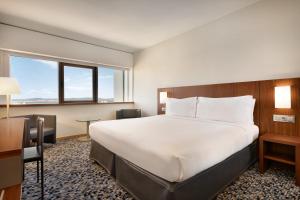 a hotel room with a bed and a desk at Ramada by Wyndham Lisbon in Lisbon