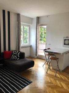 a living room with a black couch and a table at Villa Barovier Apartments in Riva del Garda