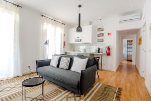 sala de estar con sofá negro y cocina en Sta Catarina - Cascais Beach Apartments, en Cascais