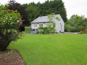 una casa blanca con un patio con césped verde en The Pavilion at Brunger House, en Tenterden