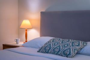 a bed with a pillow and a table with a lamp at Mitsis La Vita in Rhodes Town