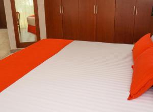 1 cama con sábanas de color naranja y blanco y armarios de madera en Hotel Viva Villahermosa, en Villahermosa