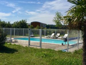 une clôture autour d'une piscine avec deux chaises dans l'établissement Les Roulottes-Gîtes de la Ferme de l'Autruche Dromoise, à Livron-sur-Drôme