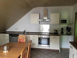 a kitchen with white cabinets and a table and a stove at Ferienwohnung Deichsel in Sundern