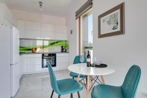 a kitchen with a white table and blue chairs at Wild Island Suite in Gdańsk