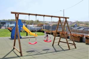 a playground with three swings and a slide at Vale de Lourinhã - Casas de Campo in Lourinhã