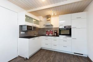 eine Küche mit weißen Schränken und einer Holzdecke in der Unterkunft FeWo Sommerhalde in Althütte