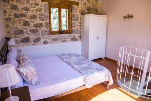 a bedroom with a bed and a stone wall at To Spiti mas in Sougia