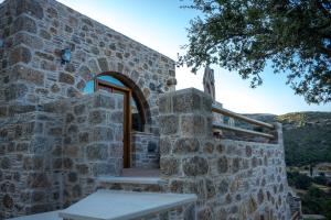 a stone building with a wooden door and stairs at To Spiti mas in Sougia