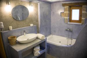 a bathroom with a sink and a tub and a mirror at To Spiti mas in Sougia