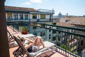 a woman laying on a chair on a balcony at Plus Florence in Florence
