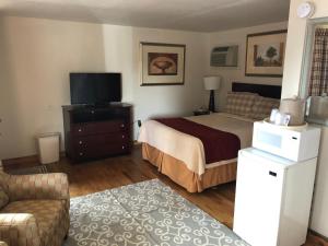 
a hotel room with a bed, television and a dresser at Rainbow Lodge and Inn in Colorado Springs

