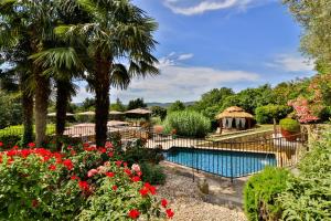 a pool in a garden with flowers and a gazebo at Le Mas de la Lombarde in Lourmarin