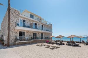 een gebouw op het strand met tafels en parasols bij Kyma Rooms & Suites in Kardamaina