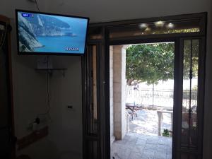 TV de pantalla plana en una pared junto a una puerta en Tamer Guest house, en Haifa