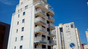 un edificio blanco con balcones en un lateral en Apta Mar del Este alquiler semanal exclusivo familias, en Playa de Gandía