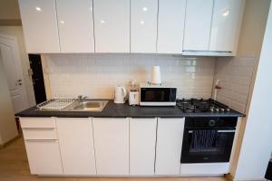 a kitchen with white cabinets and a sink and a microwave at Cris Apartament in Suceava +2 photos