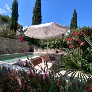 a white umbrella sitting next to a swimming pool at Maison de Maître Des-Sens in Nyons