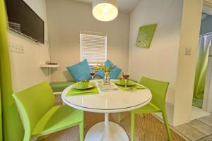 a dining room with a white table and green chairs at Beach Walk Studio in Paget Parish