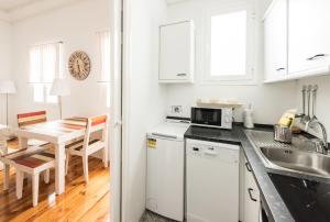 a kitchen with white cabinets and a dining table at Apartamentos Alcalá in Madrid